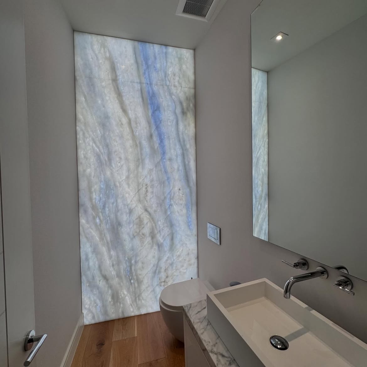 Luxury powder room with a backlit onyx-effect decorative wall panel