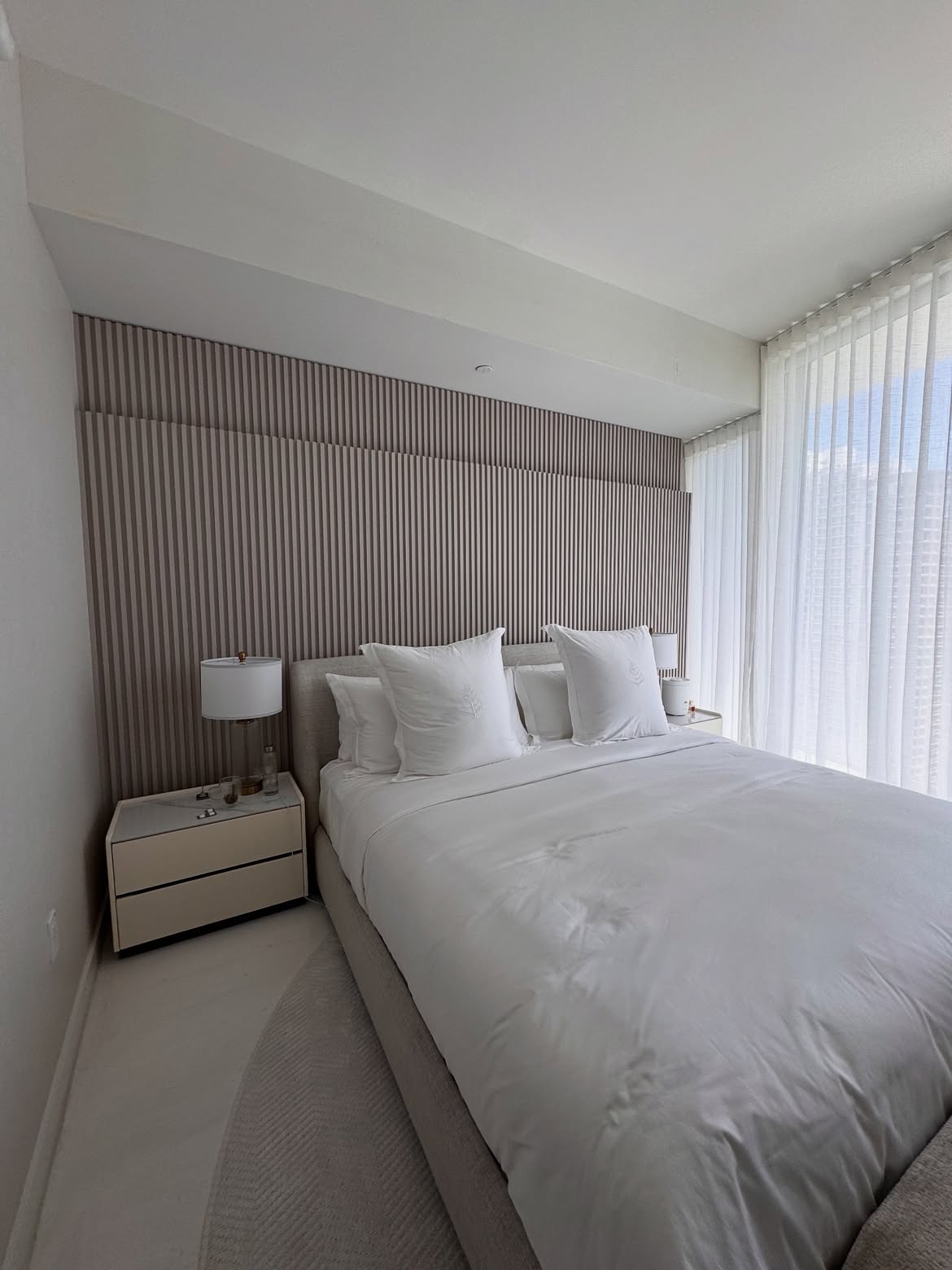 Luxury bedroom with decorative wood slat panel and custom curtains
